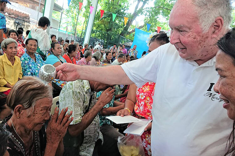 U.S. Redemptorist Father Joe Maier blesses a woman during Thai New Year festivities in 2018 at his Mercy Centre in Bangkok. The 80-year-old priest has been working in the slums of Bangkok for more than 40 years. (CNS photo/courtesy Tibor Krausz) 