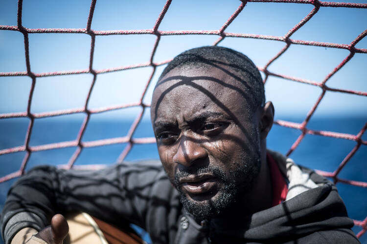 A migrant is seen in a file photo holding his guitar aboard the Sea Watch 3 German charity ship off the coast of Lampedusa, Italy. (CNS photo/Nick Jaussi, Sea-Watch via Reuters)