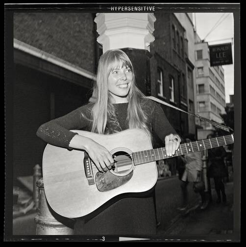 Joni Mitchell strums guitar outside the The Revolution Club, London, England, Sept. 17, 1968 (Alamy).