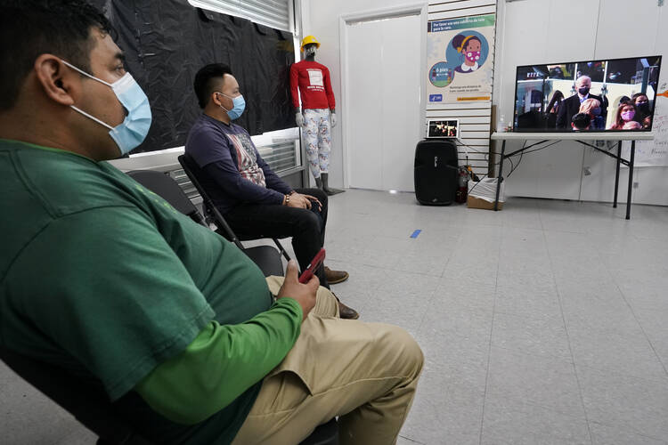 Workers Justice Project Director Gonzalo Cruz, left, and organizer Juan Carlos Romero watch President Joe Biden's presidential inauguration on TV in the Sunset Park neighborhood of Brooklyn in New York. The Workers Justice Project is a Brooklyn-based nonprofit that helps immigrants. (AP Photo/Kathy Willens)