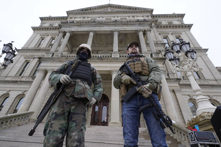 Armed men stand on the steps at the State Capitol after a rally in support of President Donald Trump in Lansing, Mich., on Jan. 6, 2021. (AP Photo/Paul Sancya, File)