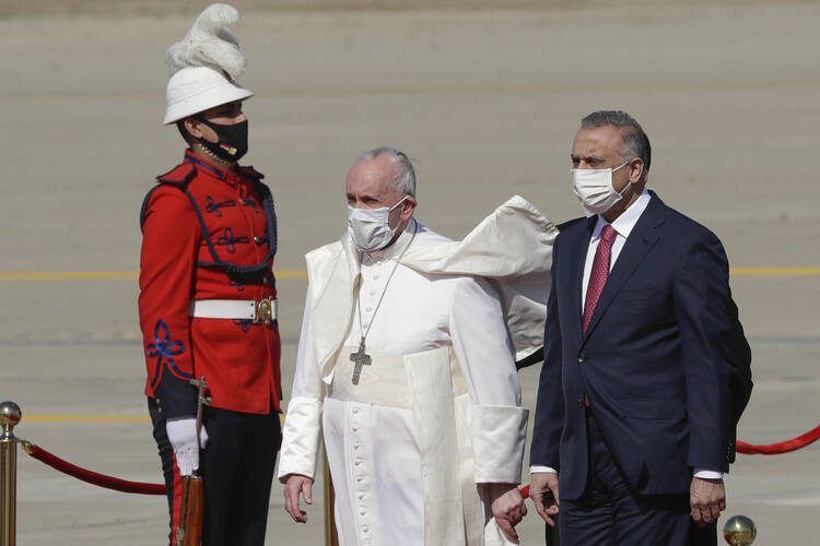Pope Francis is flanked by Iraqi Prime Minister Mustafa al-Kadhimi upon his arrival at Baghdad's international airport, Iraq, Friday, March 5, 2021.  (AP Photo/Andrew Medichini)