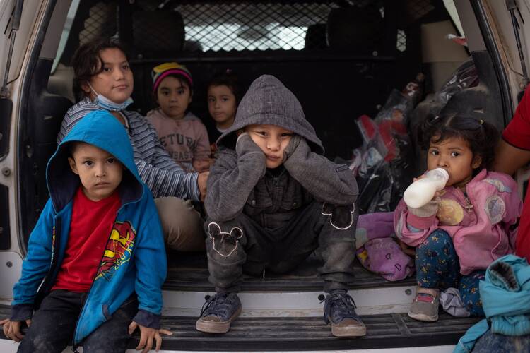 Migrant children from Central America take refuge from the rain in the back of a U.S. Border Patrol vehicle in Penitas, Texas, March 14, 2021, as they await to be transported after crossing the Rio Grande into the United States. (CNS photo/Adrees Latif, Reuters)