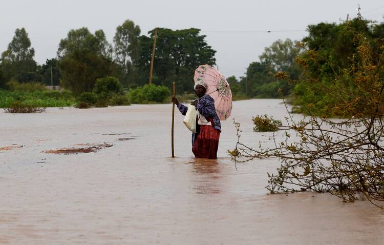A woman wades through floodwaters in Busia, Kenya, May 3, 2020. Across East Africa, flooding has resulted from months of excessive rainfall, which has also triggered landslides and mudslides. It has left thousands homeless and destroyed farmland. (CNS photo/Thomas Mukoya, Reuters)