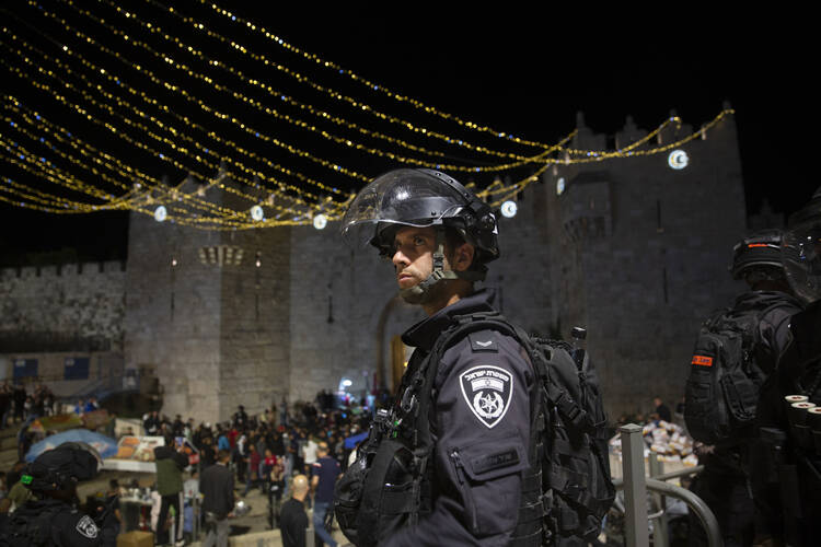 An Israeli police officer stands guard at the Damascus Gate to the Old City of Jerusalem after clashes at the Al-Aqsa Mosque compound, Friday, May 7, 2021. Palestinian worshippers clashed with Israeli police late Friday at the holy site sacred to Muslims and Jews, in an escalation of weeks of violence in Jerusalem that has reverberated across the region. (AP Photo/Maya Alleruzzo)