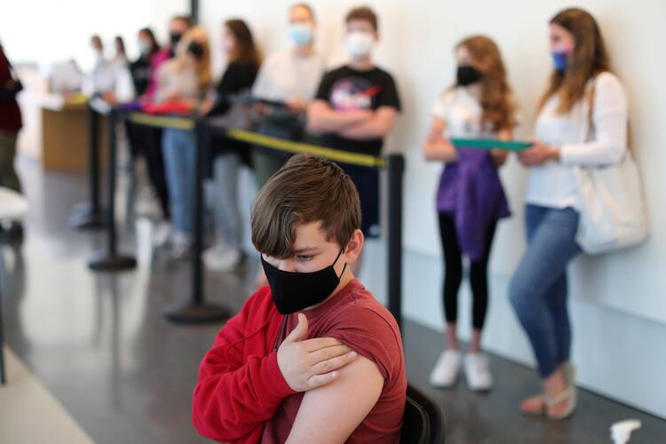 Rafael Maeder Moreira, 12, rubs his arm after receiving the Covid-19 vaccine at the Annenberg Foundation in Los Angeles on May 13. (CNS photo/Lucy Nicholson, Reuters)