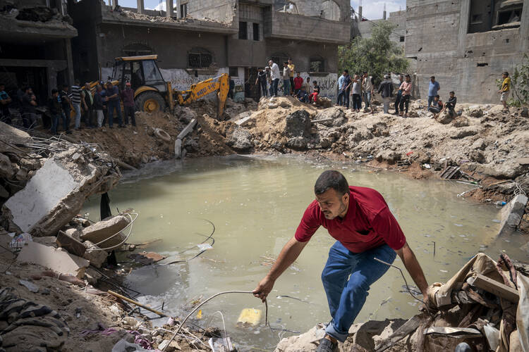 Ramez al-Masri, 39, navigates the edge of a crater where his home was destroyed by an air-strike prior to a cease-fire reached after an 11-day war between Gaza's Hamas rulers and Israel, Sunday, May 23, 2021, in Beit Hanoun, the northern Gaza Strip. (AP Photo/John Minchillo)