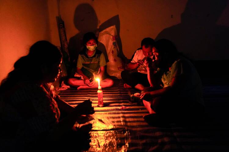Villagers fleeing the violence in Myanmar are pictured under candlelight at a school in the Thai border village of Mae Sam Laep. Cardinal Charles Bo is asking the people of Myanmar to say the rosary and participate in eucharistic adoration for peace and justice. (CNS photo/Athit Perawongmetha, Reuters)