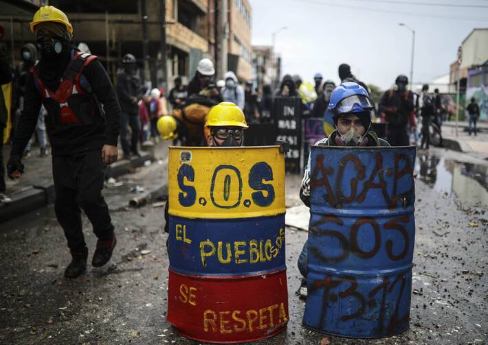 Anti-government protesters hide behind makeshift shields during clashes with the police in Bogota, Colombia, Wednesday, June 9, 2021. The protests have been triggered by proposed tax increases on public services, fuel, wages and pensions. (AP Photo/Ivan Valencia)