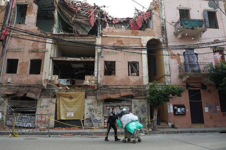 A woman wearing a protective masks pushes a cart past damaged buildings in Beirut Jan. 26, 2021, during the COVID-19 pandemic. More than half of the population of Lebanon lives in poverty. (CNS photo/Mohamed Azakir, Reuters)