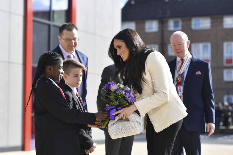 Meghan, Duchess of Sussex, is greeted by pupils at the Robert Clack Upper School in Dagenham, Essex, in eastern London, during a surprise visit to celebrate International Women's Day on March 6, 2020. (Ben Stansall/Pool via AP, File)