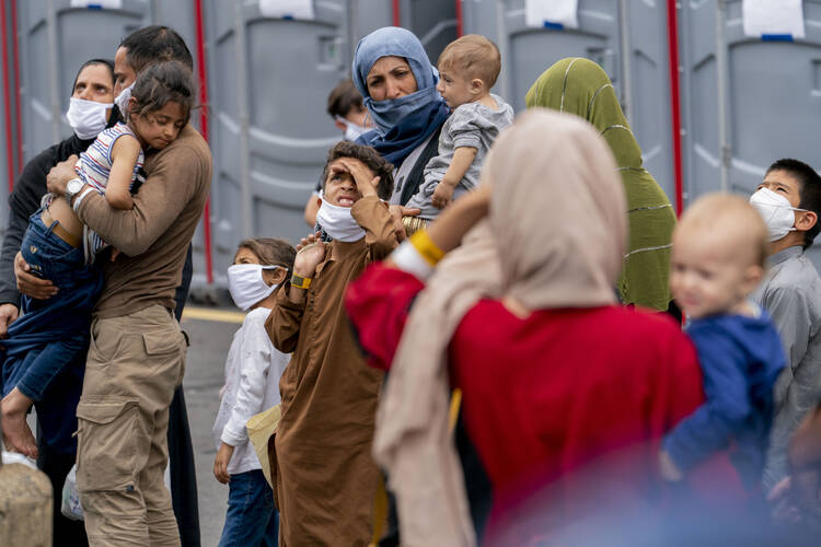 People evacuated from Afghanistan step off a bus as they arrive at a processing center.
