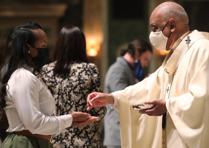 Washington Cardinal Wilton D. Gregory gives Autiyonna Johnson her first Communion as a new Catholic during the Easter Vigil at the Cathedral of St. Matthew the Apostle in Washington on April 3, 2021. (CNS photo/Andrew Biraj, Catholic Standard)