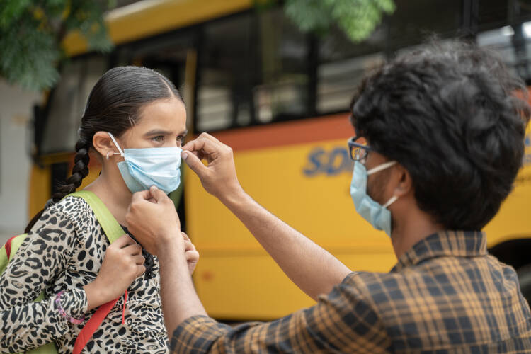 A man fixes a young girl's face mask