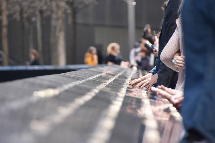 Visitors touch the names engraved in the 9/11 Memorial in Manhattan.