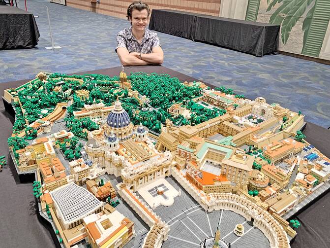 Rocco Buttliere, a LEGO architect from Chicago, kneels proudly next to the Vatican City State replica he created.