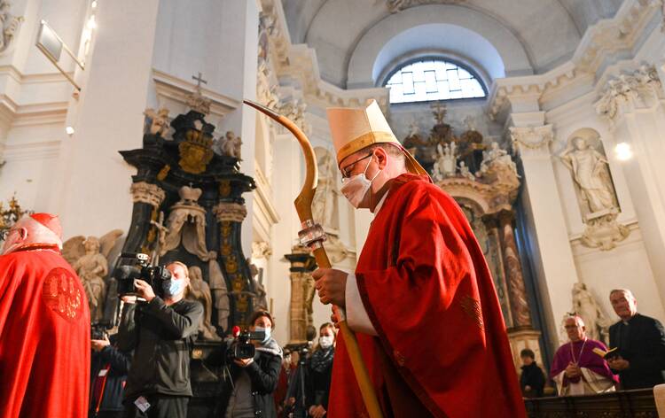 Bishop Georg Bätzing, wearing a red chasuble, carries a sharp-tipped crozier at the beginning of the autumn plenary meeting of German bishops.