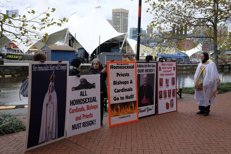 Under an overcast sky, protesters with large signs, including one that says "Homosexual Priests Bishops & Cardinals Go to Hell!"