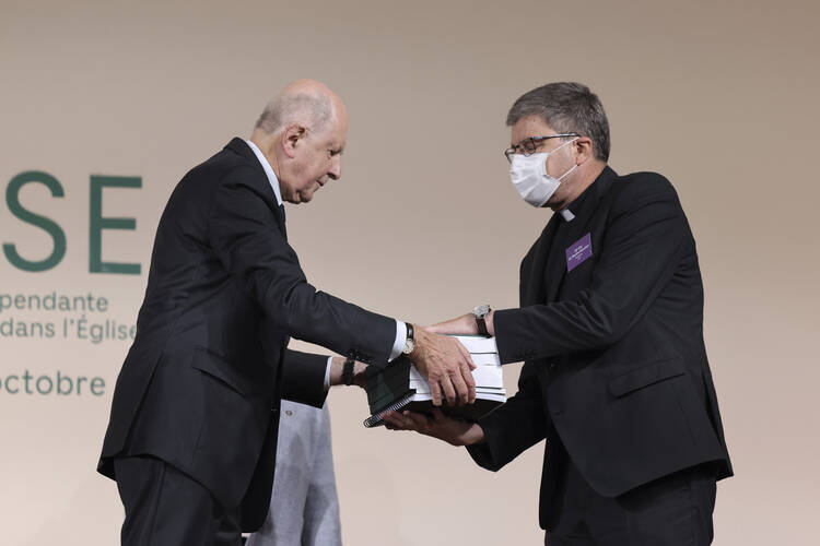 Commission president Jean-Marc Sauve, left, hands large, bound copies of the report to Catholic Bishop Eric de Moulins-Beaufort, president of the Bishops' Conference of France on Tuesday.