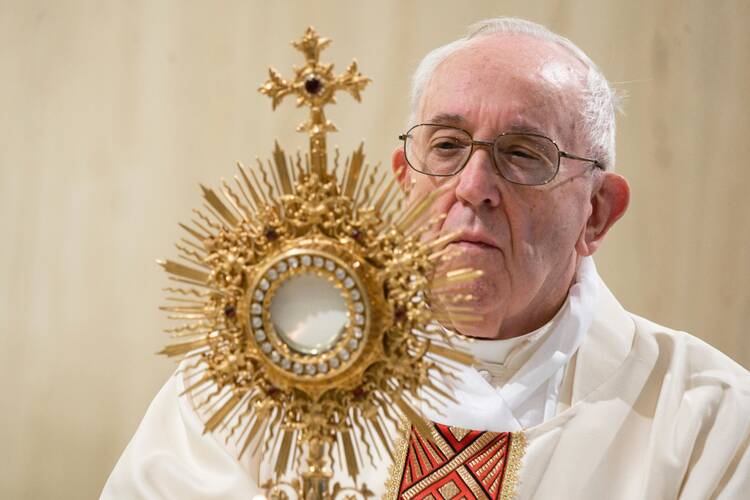 Pope Francis raises the monstrance during eucharistic adoration at the end of Mass in the chapel of his Vatican residence, the Domus Sanctae Marthae, May 5, 2020. (CNS photo/Vatican Media)