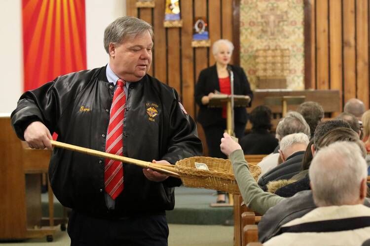Usher Gene Johann uses a collection basket during Mass at St. Anthony of Padua Church in Rocky Point, N.Y., in 2018. (CNS photo/Gregory A. Shemitz)