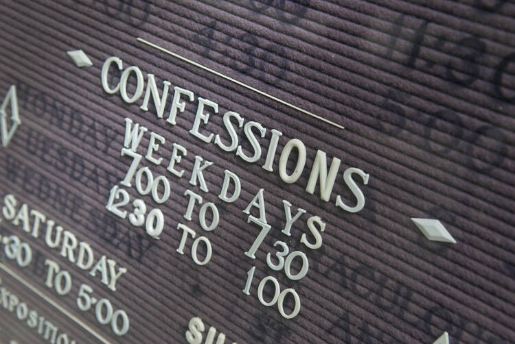 Stock close-up image of a black bulletin board with confession times.