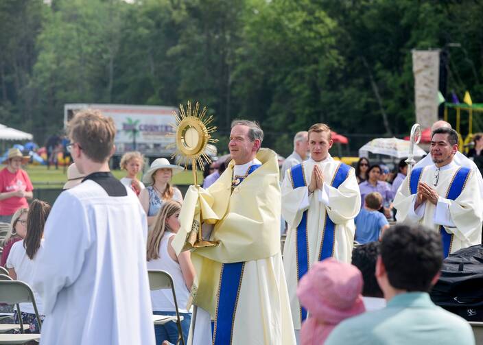Bishop Michael F. Burbidge of Arlington, Va., carries the monstrance through the crowd for eucharistic adoration outside.