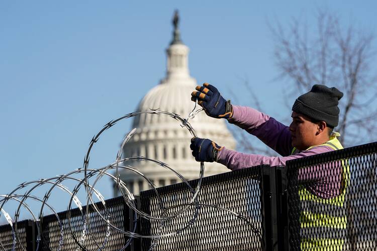 A worker in Washington removes razor wire from the top of security fencing outside the U.S. Capitol.