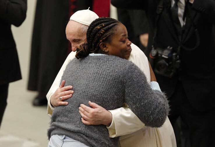 Pope Francis embraces a woman in a gray sweater during his general audience in the Paul VI hall at the Vatican.