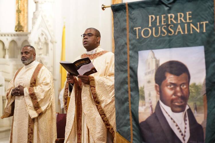 Father Alonzo Cox is assisted by Deacon Rachid Murad, left, as he celebrates a Mass marking Black Catholic History Month. Pierre Toussaint, seen on a banner at the altar, is one of six African American Catholics who are candidates for sainthood.