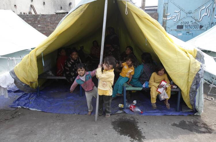 Pakistani Christian children play in front of yellow tents provided for Christian families whose homes were set on fire by a mob, in Lahore, Pakistan.