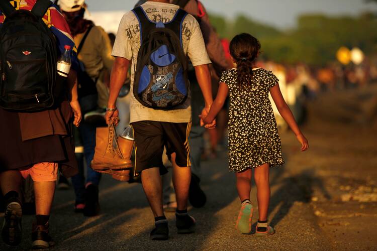 Jose Francisco from Honduras leads his 8-year-old daughter, Zuabelin, by the hand on Nov. 22, 2021, as they take part in a caravan near Villa Mapastepec, Mexico, headed to the U.S. border. (CNS photo/Jose Luis Gonzalez, Reuters)