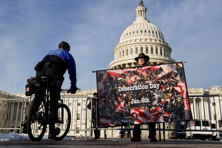 A man in Washington demonstrates near the U.S Capitol Jan. 6, 2022, holding a sign that says, “Desecration Day.”