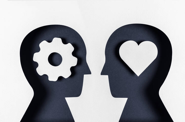 A graphic with two paper silhouettes of heads facing each other, one with a gear inside and the other with a heart.