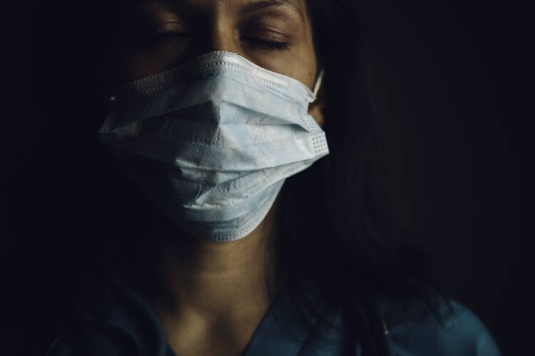 An exhausted woman wearing a surgical mask.