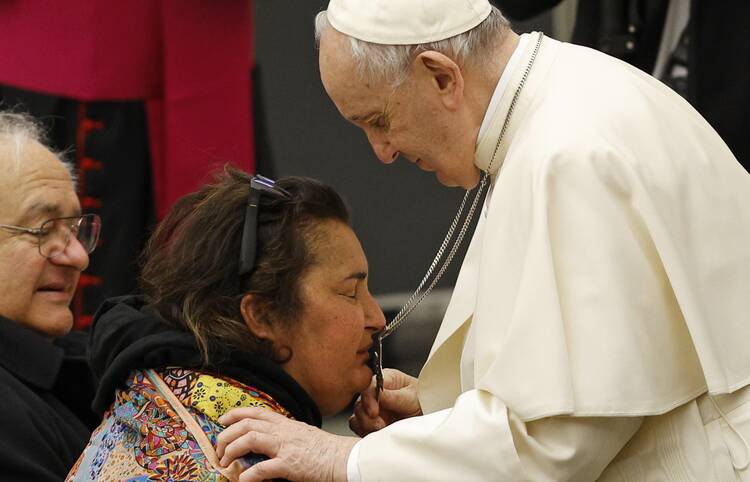 A woman kisses Pope Francis' cross as he leaves his general audience in the Paul VI hall at the Vatican Feb. 23, 2022.