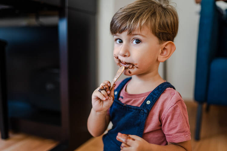 A young boy has chocolate smeared on his face after eating dessert.