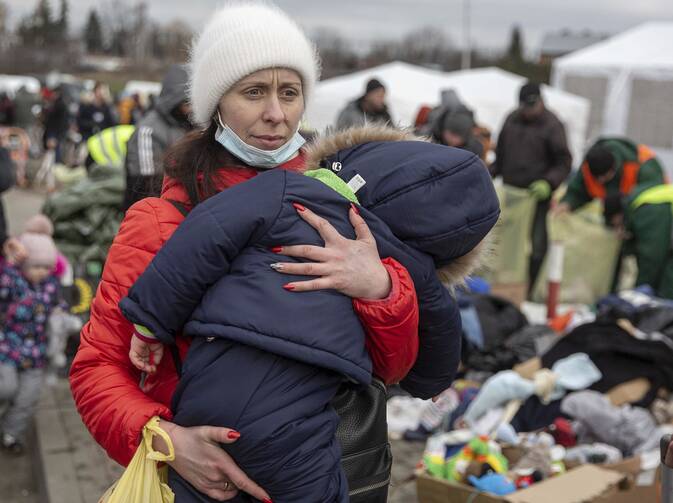 A woman carries her child as she arrives at the Medyka border crossing after fleeing from the Ukraine, in Poland, Monday, Feb. 28, 2022. The head of the United Nations refugee agency says more than a half a million people had fled Ukraine since Russia’s invasion on Thursday. (AP Photo/Visar Kryeziu)