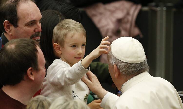 A boy touches Pope Francis' head during the general audience in the Paul VI hall at the Vatican March 2, 2022.