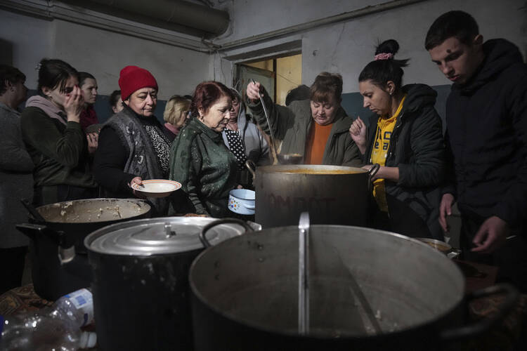 People line up to receive hot food in an improvised bomb shelter in Mariupol, Ukraine, on March 7, 2022. (AP Photo/Evgeniy Maloletka)