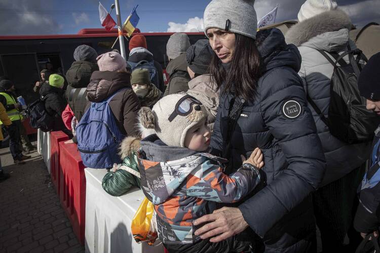 Women and children wait to board a bus heading to Przemysl after fleeing Ukraine, at the border crossing in Medyka, Poland, on March 10, 2022. (AP Photo/Visar Kryeziu)