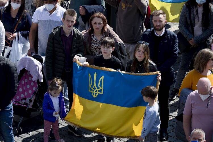Young people hold a Ukrainian flag as Pope Francis speaks to visitors gathered in St. Peter's Square at the Vatican for the recitation of the Angelus prayer March 20. (CNS photo/Vatican Media)