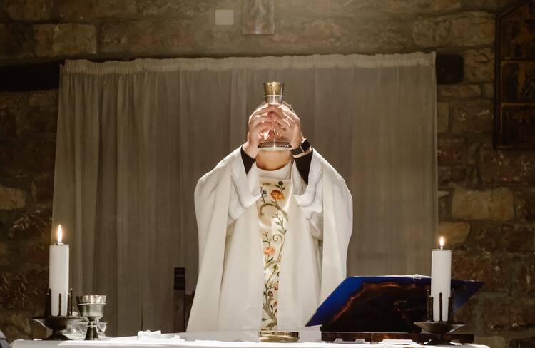 A priest lifts up the consecrated host during Mass.