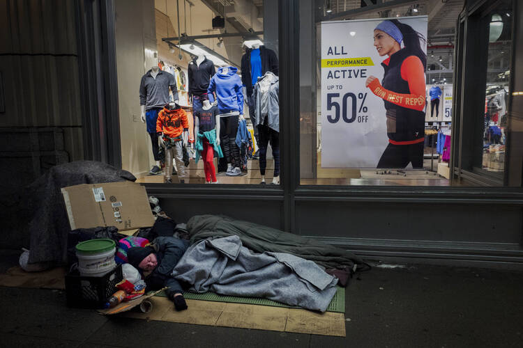 A homeless person sleeps under a blanket outside a window display in New York on Jan. 11, 2017. (AP Photo/Mark Lennihan, File)
