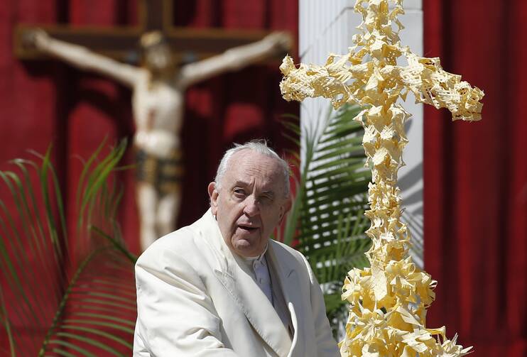Pope Francis is pictured near palm fronds in the form of a cross as he prepares to greet the crowd at the conclusion of Palm Sunday Mass in St. Peter's Square at the Vatican on April 10, 2022. (CNS photo/Paul Haring)