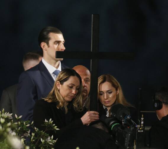 Ukrainian nurse Iryna and Russian nursing student Albina, who are friends, hold a cross at the 13th station as Pope Francis leads the Way of the Cross outside the Colosseum in Rome April 15, 2022. (CNS photo/Paul Haring)