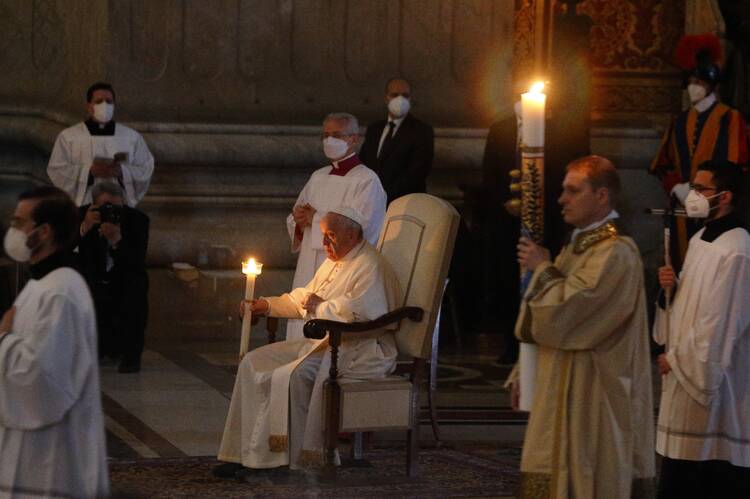 Pope Francis holds a candle as he attends the Easter Vigil celebrated by Cardinal Giovanni Battista Re in St. Peter's Basilica at the Vatican April 16, 2022. (CNS photo/Paul Haring)