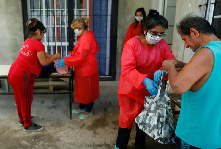 Volunteers in protective masks giving food to low-income people at a soup kitchen in Buenos Aires, Argentina, during the Covid-19 pandemic. (CNS photo/Agustin Marcarian, Reuters)