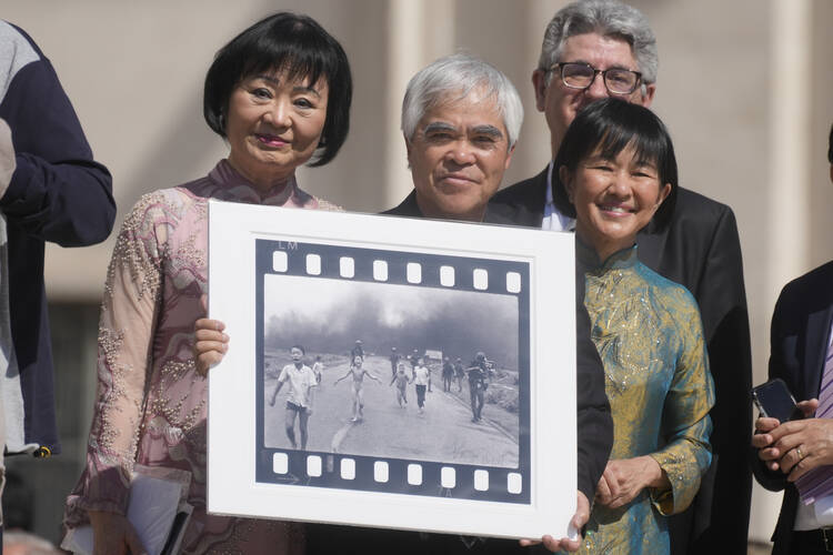 Nick Ut, center, flanked by UNESCO Ambassador Kim Phuc, left, holds “Napalm Girl,” his Pulitzer Prize-winning photo, as they wait to meet with Pope Francis  Wednesday, May 11, 2022.