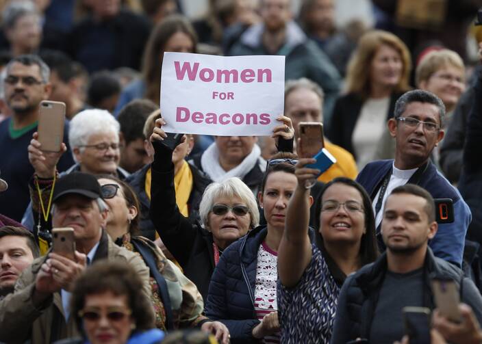 A woman holds a sign reading “Women for Deacons” as Pope Francis leads his general audience in St. Peter's Square at the Vatican Nov. 6, 2019.